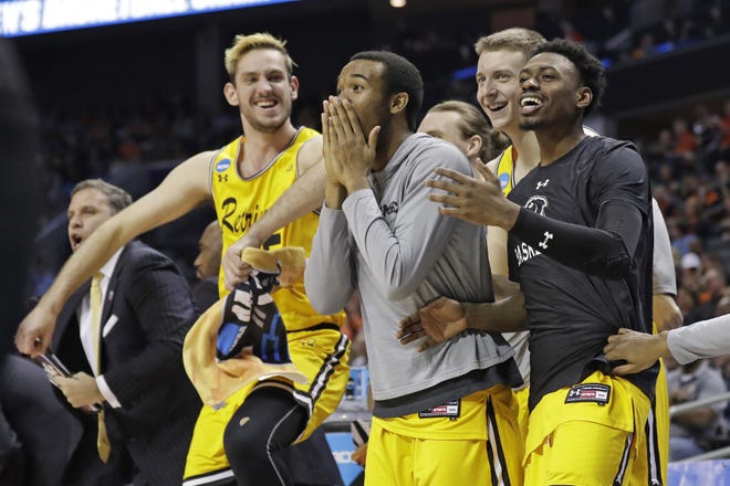UMBC players celebrate a teammate's basket during the second half against Virginia i a first-round game in the NCAA men's college basketball tournament March 16, 2018 in Charlotte, North Carolina. [Gerry Broome/The Associated Press]