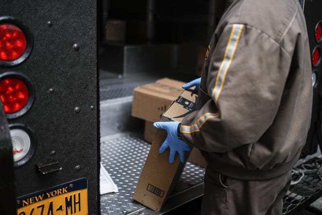 A delivery services worker wears protective gloves while making stops in midtown, Tuesday, March 17, 2020, in New York. [AP Photo/John Minchillo]