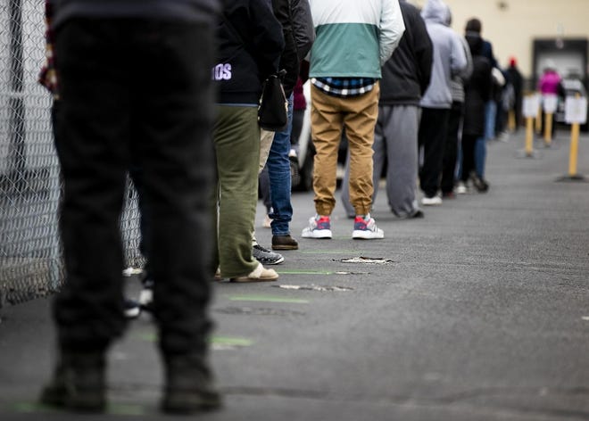Customers are asked to practice social distancing and stand on the markers on the ground as they wait in line for recreational marijuana at the In Good Health dispensary in Brockton on Monday. [Alyssa Stone/The Enterprise]