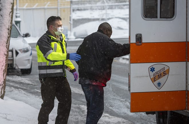 A Worcester E.M.S. paramedic assists a patient into his ambulance on Austin Street in a snowstorm Monday. Essential workers continue to do essential jobs. [T&G Staff/Rick Cinclair]