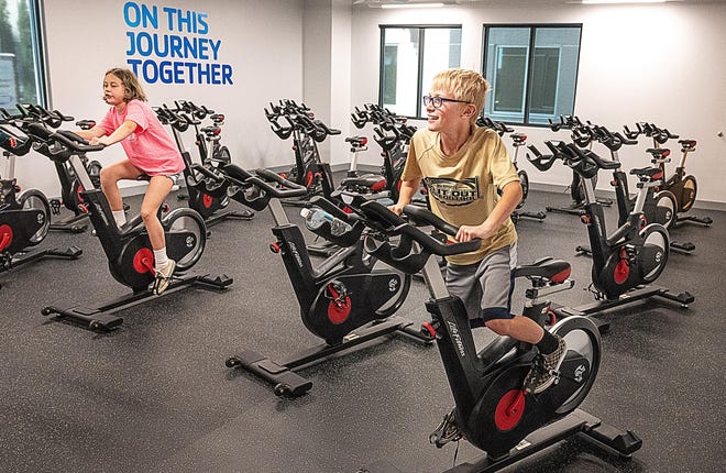 Hailey Siebel, 10, and Robert Aley, 9, use exercise bikes during a daycare at the YMCA at the Flagler Health+ Village in Murabella on Tuesday. Area YMCAs are offering child care for elementary-aged children to help working parents after local schools closed because of the coronavirus. [PETER WILLOTT/THE RECORD]