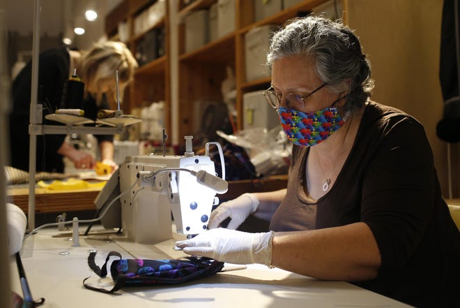 Dulce Brousset sews together a protective medical mask while Sanni Baumgaertner cuts fabric that will also be made into masks at Community in downtown Athens on Tuesday. [Photo/Joshua L. Jones, Athens Banner-Herald]