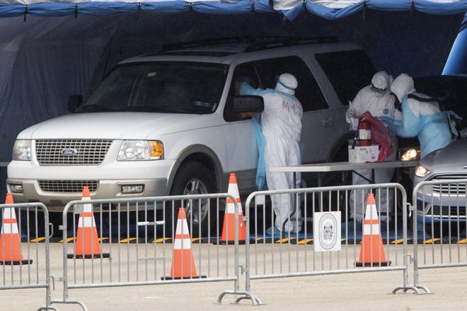 Medical workers perform a coronavirus test on driver at the Temple University Ambler campus in Upper Dublin Wednesday. [MATT ROURKE / ASSOCIATED PRESS]