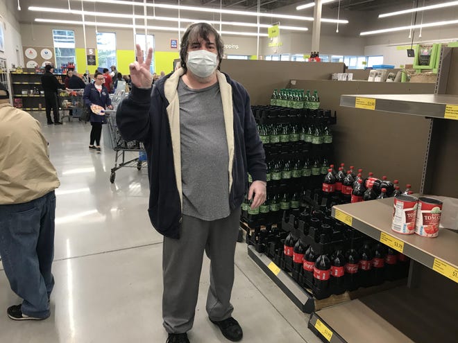 John Serdy, 55, of Levittown, flashes a peace sign as he shops at the Aldi market in Bristol Township. “I just took two (dozen) eggs, because I don’t need four. Four’s the (store) limit. The more I hoard, the less someone else has.” [JD MULLANE / STAFF PHOTOGRAPHER]