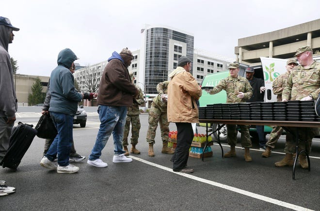 The Ohio National Guard formed an assembly line to serve meals to the homeless outside the YMCA in downtown Columbus on Monday. [Barbara J. Perenic/Dispatch]
