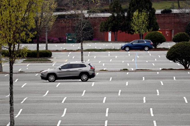 Cars drive through an empty parking lot at Southpoint Mall in Durham, N.C., Tuesday, March 24, 2020. Many non-essential businesses have closed during the coronavirus outbreak as shoppers stay away. (AP Photo/Gerry Broome)