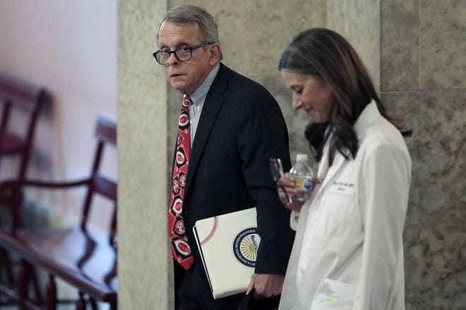 Gov. Mike DeWine and Dr. Amy Acton, director of the Ohio Department of Health, head to their daily briefing Thursday at the Statehouse in Columbus. [Joshua A. Bickel/The Columbus Dispatch]