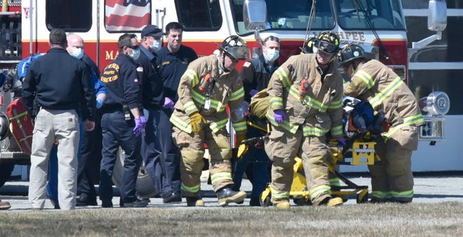 Mashpee Fire Department crews carry a man to a waiting MedFlight helicopter at the town's public safety complex. The man is being charged with murder in the death of a woman found Thursday at a Center Street apartment. [Steve Heaslip/Cape Cod Times]