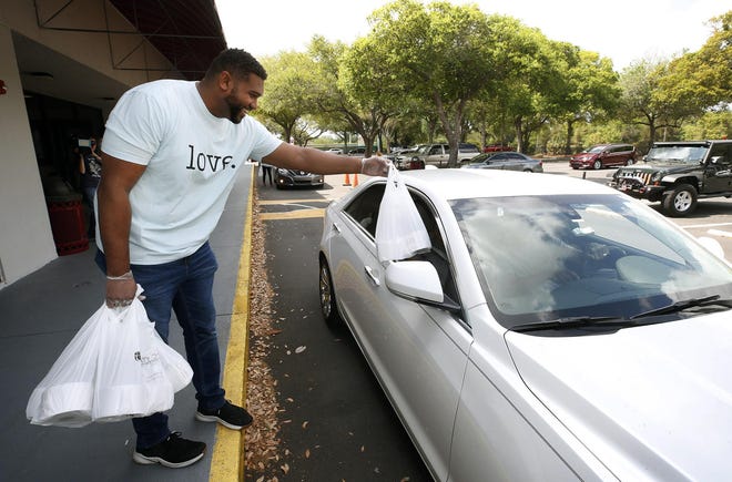Service with a smile: Timothy McCain, the young adults pastor at Trinity Church in Deltona, hands a bag of toilet paper rolls to an area resident on Thursday, March 26, 2020. Toilet paper has become difficult to find with people stocking up during the coronavirus pandemic. [News-Journal/Nigel Cook]