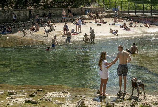 Dozens of people gather at Barton Creek below the dam at Barton Springs Pool on Wednesday March 25, 2020, the first day of the shelter in place order in Austin due to the coronavirus pandemic. [JAY JANNER/AMERICAN-STATESMAN]