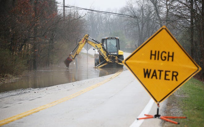 A Cuyahoga Falls street crew works on clearing a pipe to drain the water from Theiss Road in the Northampton area of Cuyahoga Falls on Saturday, March 28, 2020. [Mike Cardew/Beacon Journal]