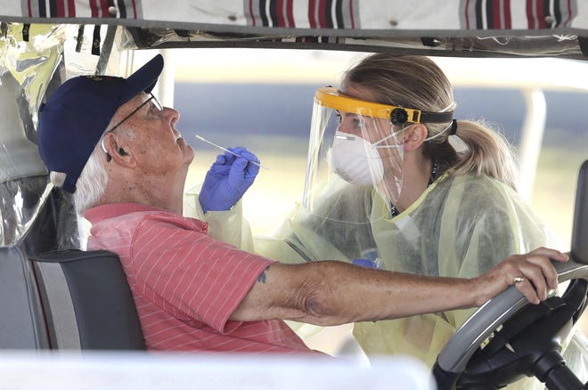 A resident of The Villages, Fla., gets tested for the coronavirus with a nasal swab at a drive-through site that accomodates golf carts, at The Villages Polo Club last week. The testing site is being operated by UF Health, with University of Florida medical students performing the tests. [Joe Burbank via AP]