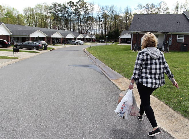 Tara Brown carries some groceries to one of the residents at Magnolia Place on Tuesday afternoon. Brown has been running errands and picking up groceries for some of the older residents in the neighborhood in Lowell. [JOHN CLARK/THE GASTON GAZETTE]