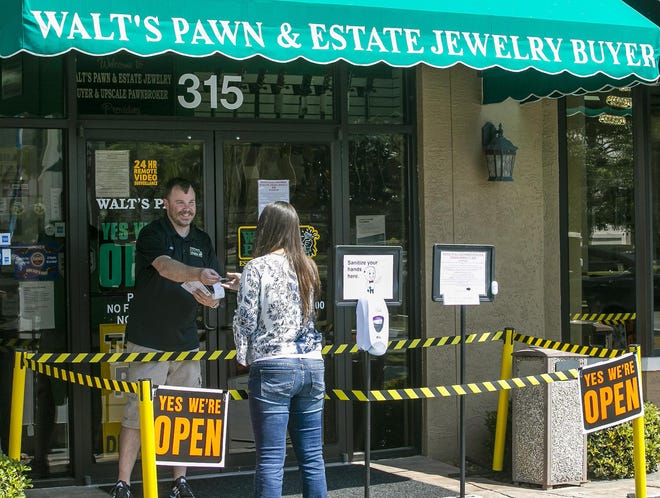 Jack Sheaves, manager at Walt's Pawn & Estate Jewelry Buyer, helps a customer while trying to conduct business as usual on Friday. "I've not experienced nothing like this I'm my lifetime. It's crazy. We do enough to keep the doors open by using Facebook and Craigslist. It's part of our responsibility to help out the community," Sheaves said. [Doug Engle/Staff photographer]