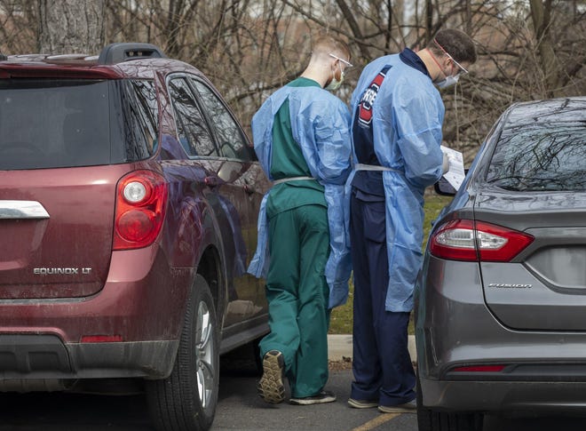 Employees from the Ohio State Martha Morehouse Outpatient Care Center perform coronavirus testing on a patient in a car on Monday, March 16, 2020. [Adam Cairns/Dispatch]