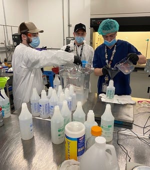 From left, tech specialist Daniel Bryant; Zachary Hall, director of manufacturing; and assistant lab tech Alex Gonzalez are seen on March 20 making a batch of hand sanitizer at the Garden Remedies facility in Fitchburg where the company grows, processes, and packages cannabis products. [Courtesy photo]