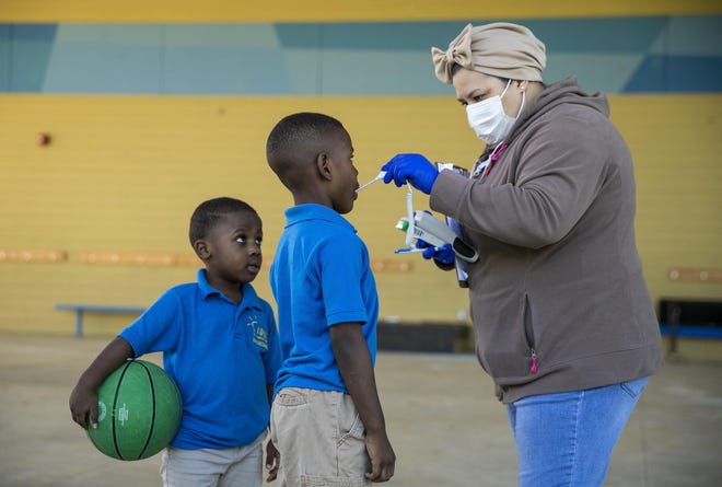 Health aide Lamya Chouika takes the temperature of De’erick Williams, 6, and his brother Dmar’ree Williams, 5, left, at the IDEA Rundberg charter school on Wednesday. Ten children of essential workers are being taught at the school amid the coronavirus pandemic. [JAY JANNER/AMERICAN-STATESMAN]