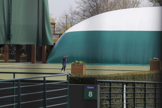 A groundsman looks at the grass on one of the outside courts at Wimbledon as it was announced that the Wimbledon tennis championships for 2020 have been cancelled..[Kirsty Wigglesworth/Associated Press]