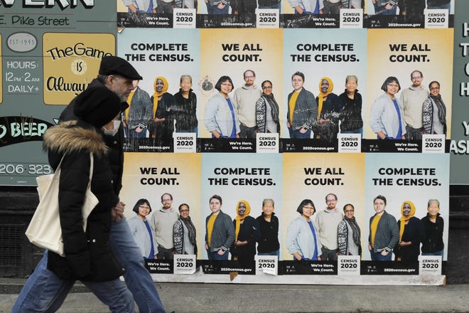 People walk past posters encouraging participation in the 2020 Census on Wednesday in Seattle's Capitol Hill neighborhood. Wednesday is Census Day, the date used to reference where a person lives for the once-a-decade count, as the U.S. is almost paralyzed by the spread of the novel coronavirus, but census officials vowed the job would be completed by its year-end deadline. [TED S. WARREN/THE ASSOCIATED PRESS]