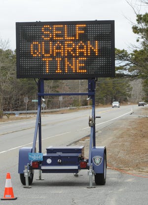 A roadside sign along Route 6 in Wellfleet reminds travelers of Gov. Charlie Baker's advisory that they self-quarantine for 14 days. [PHOTO BY MERILLY CASSIDY]