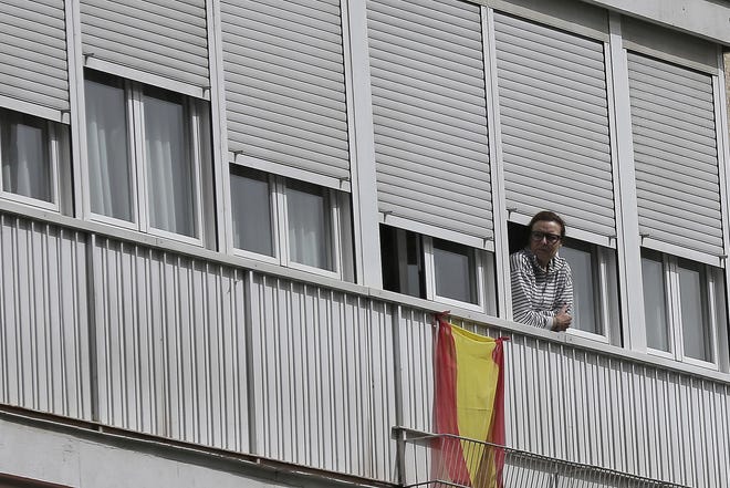A woman looks out from a balcony in Madrid, Spain, on March 19. Residents are snitching on businesses and neighbors as authorities worldwide work to enforce business shutdowns and stay-at-home orders. [ASSOCIATED PRESS FILE PHOTO]