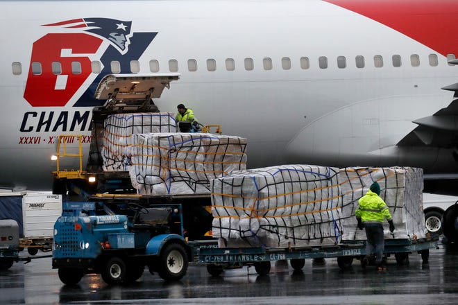 Palettes of N95 respirator masks are off-loaded from the New England Patriots football team's customized Boeing 767 jet on the tarmac, Thursday, April 2, 2020, at Logan Airport in Boston, after returning from China. The Kraft family deployed the Patriots team plane to China to fetch more than one million masks for use by front-line health care workers to prevent the spread of the coronavirus. (AP Photo/Elise Amendola)