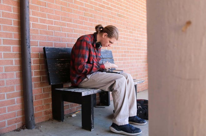 Cameron Knepper, a 16-year-old sophomore, sits on a bench and completes his assignments at North Lenoir High School Friday, April 3, while he uses the school’s WiFi. [Brandon Davis/Kinston Free Press]
