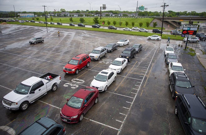 Hundred of vehicles poured out of the parking lot of Nelson Field at Reagan Early College High School in Northeast Austin on Saturday as people picked up boxes of free food from the Central Texas Food Bank. [RICARDO B. BRAZZIELL/AMERICAN-STATESMAN]