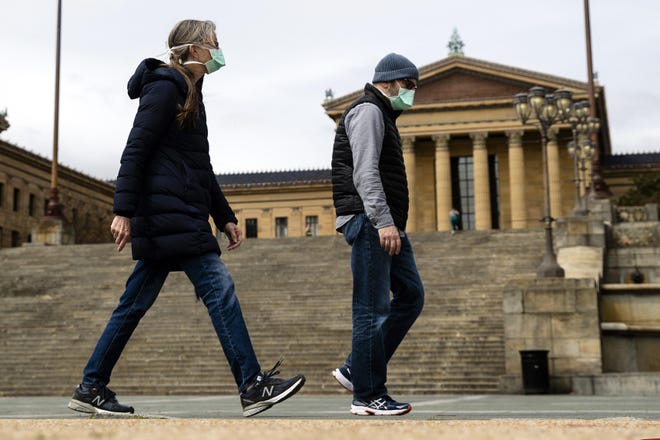 A couple in protective masks walk past the Philadelphia Museum of Art in Philadelphia on Friday. The museum has temporarily closed due to the COVID-19 pandemic. [AP Photo/Matt Rourke]