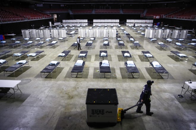 A worker moves items at a federal medical station as it is set up as a field hospital at Temple University's Liacouras Center in Philadelphia, Monday, March 30, 2020. (AP Photo/Matt Rourke)