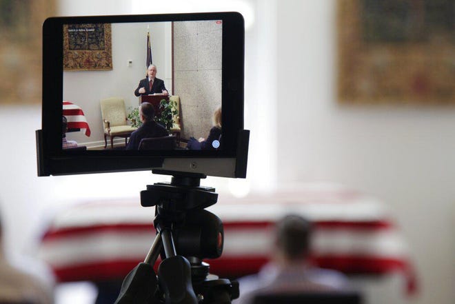 In this Friday, April 3 photo, a tablet livestreams the funeral of J. Robert Coleman in Lexington, S.C. Following CDC guidelines during the coronavirus outbreak, Thompson Funeral Homes asked Coleman's family to invite fewer than 10 people to his service. (AP Photo/Sarah Blake Morgan)