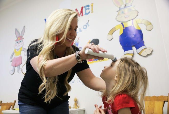 Lindsey Whitley, owner of Miss Lindsey’s Child Care & After School, LLC, checks 3-year-old Anna Decker’s temperature with a temporal scanner Tuesday, April 7, at the child care facility in Kinston. [Brandon Davis/Kinston Free Press]