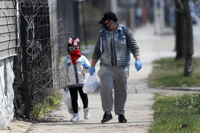Erica Harris, right, and her daughter Jordan wear their protective masks as they walk back home on Tuesday after getting a lunch and homework from the child's school on Chicago's south side. Gov. JB Pritzker on Friday called for increased testing as part of a plan to help communities hit hardest by the coronavirus pandemic. The death rate from COVID-19 is much higher for black Americans than for whites. [CHARLES REX ARBOGAST/THE ASSOCIATED PRESS]
