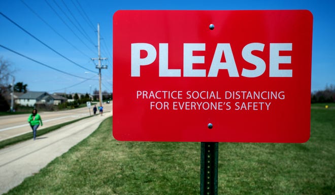 A sign urges social distancing along the trails and sidewalks and on the disc golf course on the Northwoods Church property in Peoria. [MATT DAYHOFF/JOURNAL STAR]