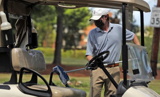 Connor Chitty uses disinfecting soap to clean the golf carts at Cleveland Country Club on Thursday. The club is extending golfing to non club members. [Brittany Randolph/The Star]
