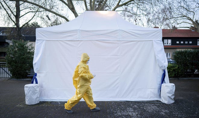 Nina Leimer, 20 years old, paramedic and second semester medical student, goes into a tent next to her mother's medical practice in Berlin, Germany, Monday, March 30, 2020. From 06.00 a.m. to 09.00 a.m., throat swabs are taken for testing for the coronavirus and blood samples are taken for the possible detection of antibodies against the coronavirus are taken at the tent. (Kay Nietfeld/dpa via AP)
