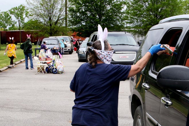 Tammy Benton wears bunny ears as she passes out prizes during the Pay It Forward — Fort Smith Community Easter Drive-Thru Fun Day and Fundraiser at the Fort Smith Trolley Museum, 100 S 4th Street, Saturday, April 11,2020. For a $2 donation per car, children in each car received a gift bag with colored plastic eggs filled with candy and prize coupons for 10 grand prize coupons as well as 150 smaller prize coupons. Proceeds from the event will be used to fill the charity's food for clients as well as donating money to smaller charities. [JAMIE MITCHELL/TIMES RECORD]
