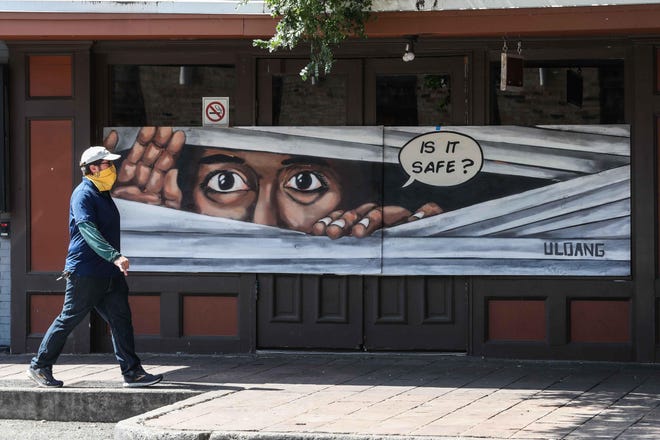 A man walks in front of a mural on Sixth Street wearing a mask amid the coronavirus pandemic on Monday, April 27, 2020. [LOLA GOMEZ / AMERICAN-STATESMAN]