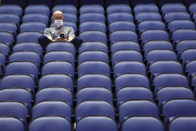 Fan Mike Lemcke sits in an empty Greensboro Coliseum after the ACC tournament men’s basketball games were canceled on March 12. [BEN MCKEOWN / ASSOCIATED PRESS]