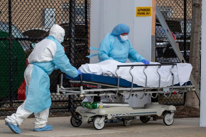 Medical personnel wearing personal protective equipment remove a body from the Wyckoff Heights Medical Center to refrigerated containers parked outside, Thursday, April 2, 2020 in the Brooklyn borough of New York. As coronavirus hot spots and death tolls flared around the U.S., the nation's biggest city was the hardest hit of the all, with bodies loaded onto refrigerated morgue trucks by gurney and forklift outside overwhelmed hospitals, in full view of passing motorists.  (AP Photo/Mary Altaffer)