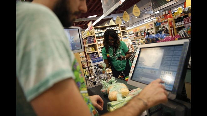 Whole Foods cashier Jason Ellsworth rings up groceries purchased by Instacart shopper Kara Pete. The supermarket chain is partnering with start-up Instacart to deliver groceries to shoppers' doorsteps. (Robert Gauthier/Los Angeles Times/TNS)