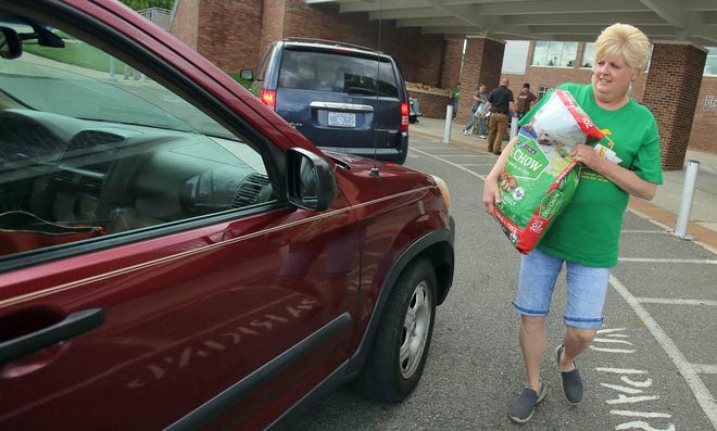 Jane Ledbetter takes a bag of dog food to a car at a pet food giveaway hosted by Clifford’s Army Rescue Extravaganza and Cleveland County Animal Services on Monday. [Brittany Randolph/The Star]