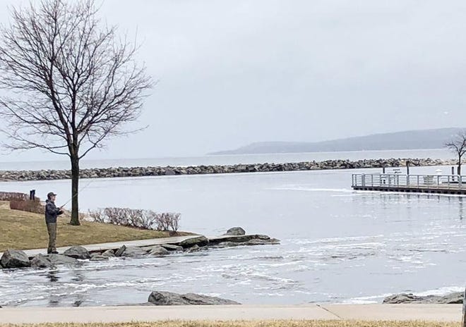 An angler tries his luck near the mouth of the Bear River in Petoskey’s Bayfront Park Sunday, just inches from the water’s edge. When water levels are at more normal levels, anglers regularly sit on the rocks, now covered by water, to fish. Visible In the background, the water level is less than a foot from the top of the Petoskey Municipal Marina’s “D” dock. [Steve Zucker/News-Review]