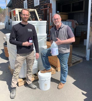 David Woods, left, and his father, Dave Woods, who together founded Wiggly Bridge Distillery in York, Maine, in 2013, show off samples from the first batch of hand sanitizer they produced in March and April 2020, with help from Stonewall Kitchen, during the COVID-19 pandemic. [Courtesy/Amber Woods, Wiggly Bridge Distillery]