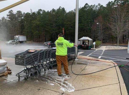 James Dalton, co-owner of Revive Painting & Powerwashing, a Medford -based company, sanitizes the shopping carts at Murphy's Fresh Market in Medford. He and his business partner Tom Davis are donating their services to several grocery stores in their town during the coronavirus crisis. [COURTESY TOM DAVIS]
