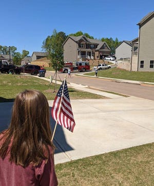 A girl in Jefferson waves the American flag as public safety vehicles drive through her neighborhood in a shelter-in-place parade. [Photo courtesy of Jefferson Fire Department]