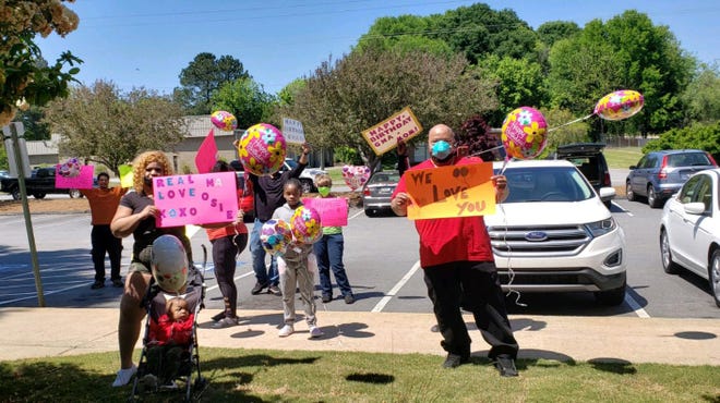 The family of Osie Watson gathers outside her nursing home window to celebrate her 77th birthday on Thursday. [Contributed photo]