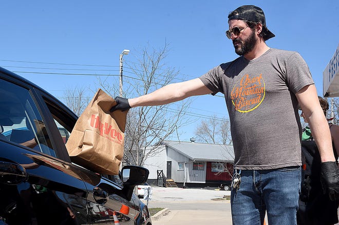 Bryan Maness of Ozark Mountain Biscuit Company hands out a ’Scrappy Meal’ at the first event Cafe Berlin on March 30. [Don Shrubshell/Tribune]
