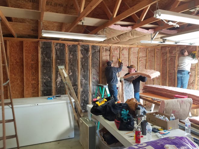 Augusta's Community Caring Center volunteers install insulation in a garage. The ACCC received 100 boxes of food for distribution for Saturday. [SUBMITTED]