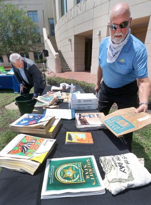 Volusia County Chair Ed Kelly, right, lays out objects from a time capsule that was buried in 1995, as County Manager George Recktenwald pulls more items out, at the Thomas C. Kelly Administration Center in DeLand on Wednesday, April 22, 2020. As part of this year’s Earth Day celebration, county officials packed another time capsule with items from 2020 and lowered it into the ground, to be opened in 2045. [News-Journal/David Tucker]